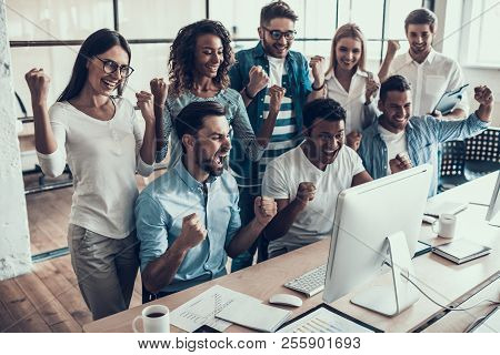 Young Smiling Business Team Celebrating In Office. Group Of Young Happy Collegues Celebrating In Mod