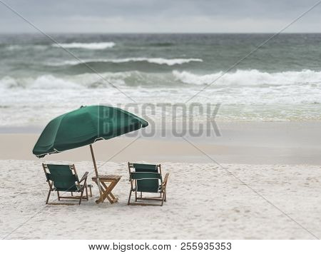 Vintage Wood And Canvas Beach Lounge Chairs And Umbrella On Deserted Stormy Beach. Selective Focus, 