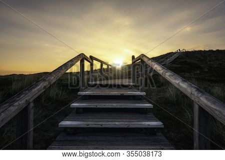 Wooden Stairs On Sylt Island At Sunrise. Sylt Coastline With The Sun Behind Grassy Dunes. Hiking Tra
