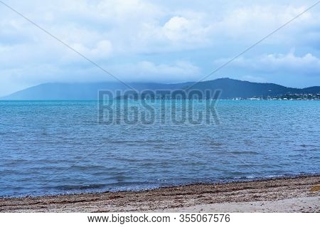 A Light Shower Of Rain Coming Across The Ocean From A Far Shore In A Bay