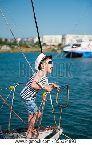 Delightful Funny Little Kid In Captain White Hat And Sunglasses Laughing On Sea Yacht Board During S