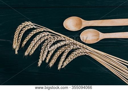 Spikelets Of Ripe Wheat And Wooden Spoons On The Kitchen Table