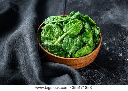 Young Raw Spinach In A Wooden Bowl. Black Background. Top View