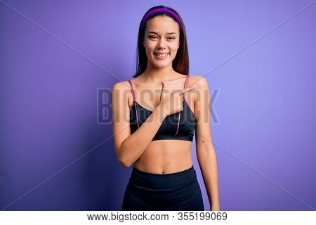 Young beautiful sporty girl doing sport wearing sportswear over isolated purple background cheerful with a smile on face pointing with hand and finger up to the side with happy and natural expression