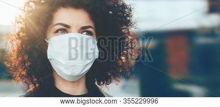 Lovely Curly Haired Caucasian Lady Protecting Herself From Viruses While Wearing Special Mask
