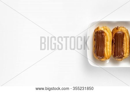 Copy Space. Fragment Plate Custard Cakes With Chocolate Icing On A White Background.