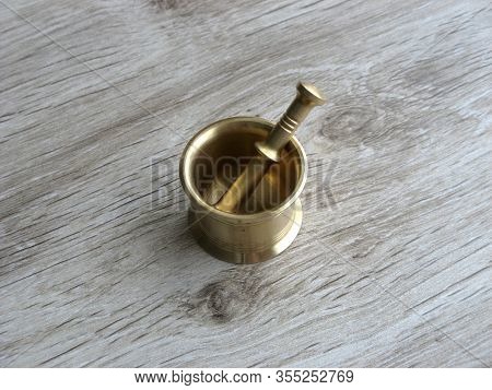 Miniature Brass Mortar And Pestle On Wooden Background. Traditional Tools. Close Up.