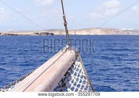 Bow Of A Cruise Ship On The Sea With A Rocky Cliffs In The Distance