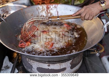 Street Food In Thailand. Deep-fried Chicken Using A Large Frying Pan With Boiling Oil. Stirring The 