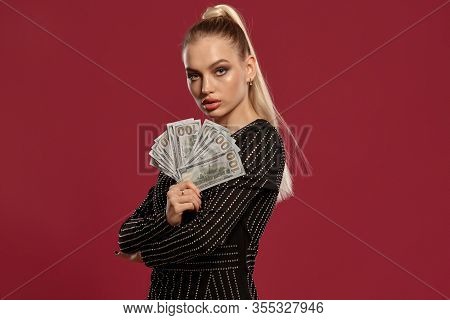 Blonde Girl With Ponytail, In Black Dress In Rhinestones. She Holding Some Cash, Posing Sideways On 