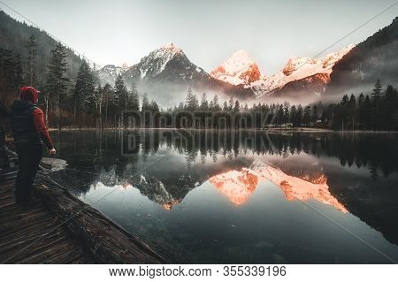 Male Hiker Standing At Mountain Lake Schiederweiher Watching The Sunrise In Austria