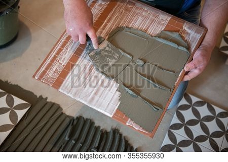 Tiler laying the ceramic tile on the floor. Professional worker makes renovation. Construction. Hands of the tiler. Home renovation and building new house