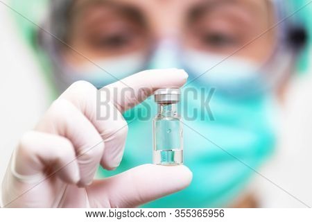 A Doctor In Medical Gloves And Mask Holding An Ampula With Vaccine. Close Up Shot. Coronavirus, Epid