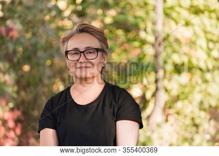 Pensive, Sad Asian Woman In A Black T-shirt In The Park, A Little Gray Hair, Sunny Day In Autumn, Sp