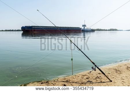 Fishing Rod Against Tanker Barge With Grain On The Ukraine Dniepr River. Water Logistic