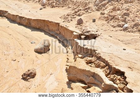 Background Of Yellow Sand With Small Stones After Rain. Soil Erosion After Heavy Rainfall And Precip