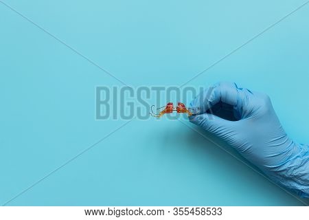 Hand Of Medic Wearing Blue Latex Glove Holding Retainer Orthodontic Appliance On Blue Background. Te