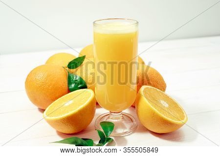 A Glass Of Fresh Orange Juice And Orange Fruits On A Wooden Table. Healthy Food.
