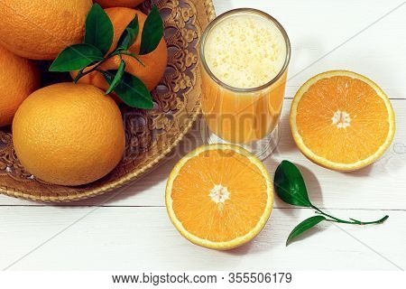 A Glass Of Fresh Orange Juice And Orange Fruits On A Wooden Table. Healthy Food.