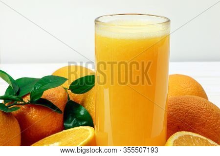 A Glass Of Fresh Orange Juice And Orange Fruits On A Wooden Table. Healthy Food