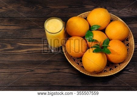 A Glass Of Fresh Orange Juice And Orange Fruits On A Wooden Table. Healthy Food.