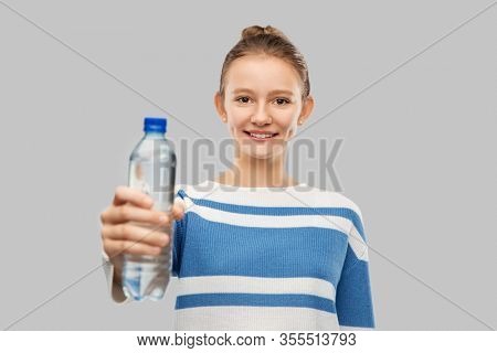 drink, health and people concept - happy smiling teenage girl in pullover with bottle of water over grey background