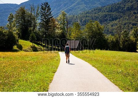 Young Woman With Backpack Hiking Along The Path In The Slovenian Countryside. Bohinj