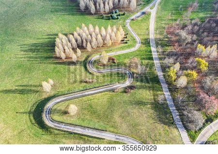 Aerial Top View Of City Park In Autumn With Long Winding Bicycle Lane And Footpath