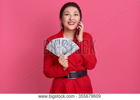 Horizontal Portrait Of Cheerful Beautiful Pretty Woman Smiling Sincerely, Holding Smartphone And Fan