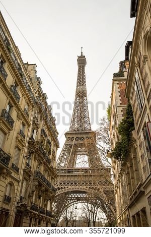 Small Paris Street With View On The Famous Paris Eiffel Tower On A Cloudy Rainy Day.