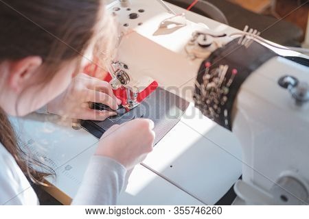 Seamstress Doing Precise Work, Shoulder View. Needlewoman At Overlock Sewing Machine Doing Professio