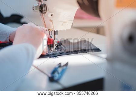 Seamstress Doing Precise Work, Close-up View. Needlewoman At Overlock Sewing Machine Doing Professio