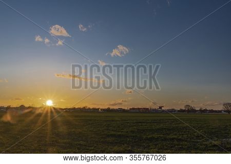 Sunset On Green Field Near Shops And Markets In Budweis City