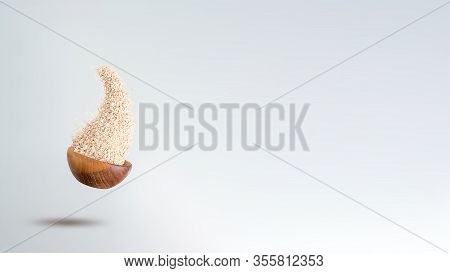 Oatmeals Flakes Flying Out From Wooden Bowl To Grey Background. Banner Format. Copy Space. Healthy B
