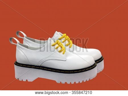 White Leather Platform Shoes Isolated On Red Background. Classic Shoes On A High Black Tractor Platf