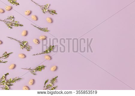 Frame Made Of Flowers And Easter Eggs On A Purple Pastel Background. Greeting Card Concept With Copy