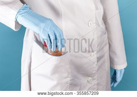 Doctor In A White Medical Gown And Blue Gloves On A Blue Background Hides A Jar Of Yellow Urine For 