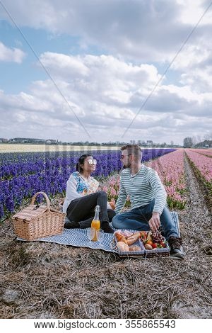 Spring Flower Season In The Netherlands, Couple Having A Picnic During Sprin In The Bulb Region By L