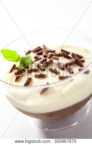 Vanilla and chocolate cream mousse decorated with chocolate chips and mint in restaurant glass isolated. Delicious creamy mousse, cocoa panna cotta or gourmet pudding souffle closeup