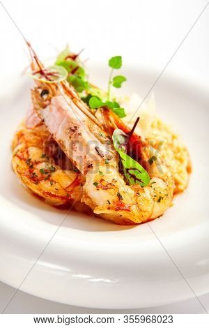 Risotto tom yam with argentinian shrimp. Delicious thai dish with seafood closeup view. Traditional asian meal with rice and aromatic greenery. Food composition on white plate. Restaurant delicacy