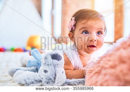 Beautiful infant happy at kindergarten around colorful toys lying on blacket