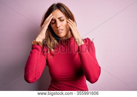 Young beautiful brunette woman wearing casual sweater stnding over pink background suffering from headache desperate and stressed because pain and migraine. Hands on head.