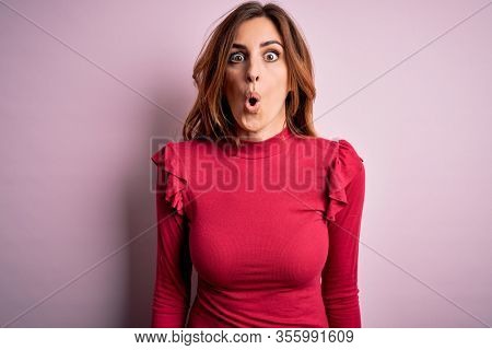 Young beautiful brunette woman wearing casual sweater stnding over pink background afraid and shocked with surprise expression, fear and excited face.