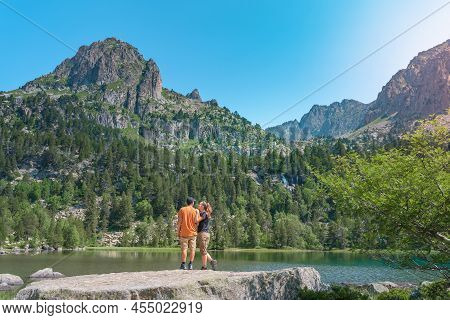 Young Attractive Couple Holding Hands In A Beautiful Lake In The Mountains In Summer During Sunset. 