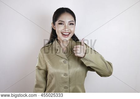 A Young Asian Woman In Brown Khaki Uniform Showing Thumbs Up Or Ok Sign. Indonesian Government Worke