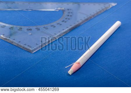 White Tailor's Marker And A Pattern Lie On A Blue Fabric