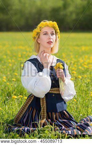 Young Woman In National Clothes Wearing Yellow Dandelion Wreath In Spring Field. Ligo