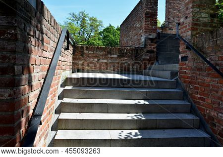 Stairs And Railings Of Exposed Brick Smooth Surface. Metal Railings And Benches In The Corners Of Th