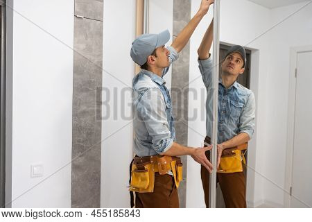 Employee Furniture Assembler In White T-shirt And Jumpsuit Checks Wooden Sliding Door Of Modern Ward