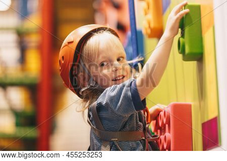 School Kids Wearing Helmets Playing On The Climbing Wall. Happy Boy Hanging On Climbing Rope And Cli